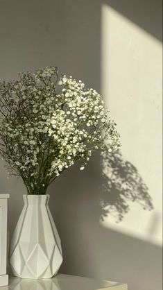 a white vase filled with baby's breath sitting on top of a table