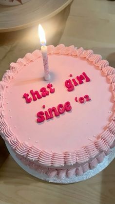 a pink cake with the words that girl since or written on it and a lit candle