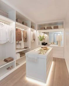 an image of a white closet with clothes on shelves and lights in the corner,