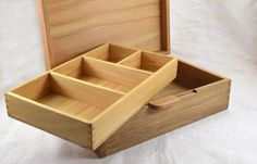 an open wooden box on a white background with the lid opened to show compartments for various items