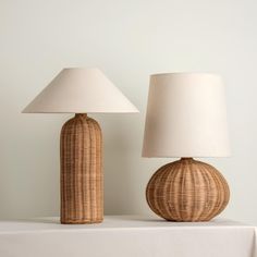 two wicker lamps sitting on top of a table next to a white lamp shade