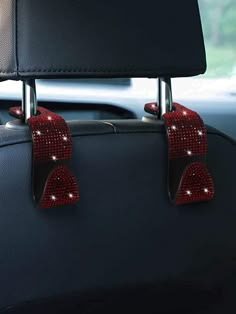 two red hearts are attached to the back of a car seat with silver hardware and sequins