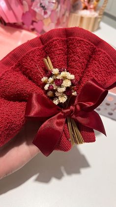 a hand holding a red bow with flowers in it