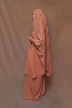 Introducing Orange Moira Prayer Umrah Gown with Niqab Feature from Annah Hariri. This beautiful gown is made from high-quality Nada abaya fabric and features super light, stretchy jersey sleeves for ultimate comfort. The elasticated waistband and full skirt ensure a flattering and secure fit, while the khimar can be tied at the back of the head for added coverage.But the best part? This gown can also be transformed into a niqaab with just a few simple stitches. So whether you're performing Umrah Elegant Solid Niqab For Eid, Long Niqab With Dabka For Eid, Elegant Niqab For Eid, Long Dabka Niqab For Eid, Modest Wedding Niqab For Eid, Modest Style Khimar For Wedding And Eid, Long Khimar For Wedding Eid Festival, Long Khimar For Wedding And Eid, Floor-length Wedding Khimar With Dabka