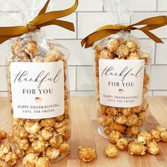 two bags filled with caramel popcorn sitting on top of a wooden table next to each other