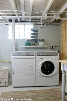 a white washer and dryer in a room with exposed pipes above the washer