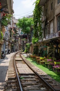 a train track running through an alley with tables and chairs lined up along the side