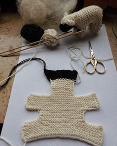 a knitted piece of clothing sitting on top of a table next to scissors and yarn