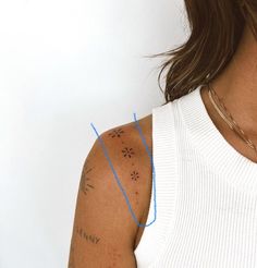 a woman with tattoos on her arm and shoulder is looking at the camera while wearing a white tank top