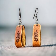 the earrings are made from wood and have leaves engraved on them, along with silver earwires