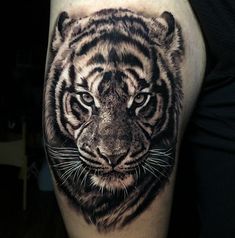 a black and white tiger tattoo on the right thigh, with an intense look to it's face