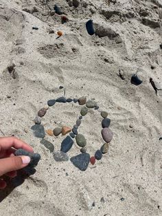 someone is making a heart out of rocks in the sand