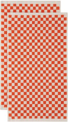 two orange and white checkered placemats on top of each other, one in the