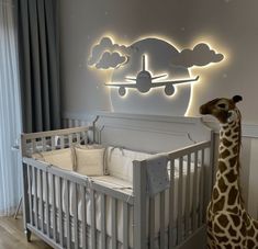 a giraffe standing next to a baby's crib in a room