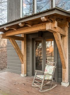 a rocking chair sitting on top of a wooden porch next to a tall gray building