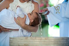 a woman is holding a baby in her arms and pouring water out of a bucket