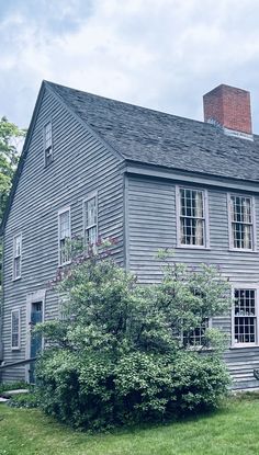 an old gray house sitting on top of a lush green field