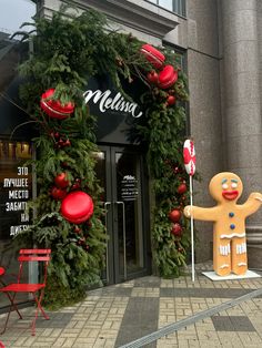 a christmas display in front of a building with decorations on the outside and large gingerbread man holding a candy cane