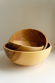 three wooden bowls sitting side by side on a white table top, with one empty bowl in the middle