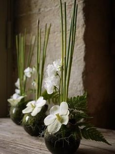 three vases filled with white flowers on top of a wooden table