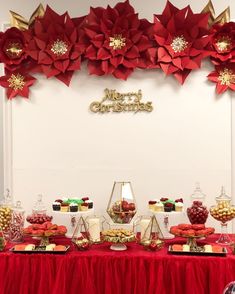 a red table topped with lots of candy and poinsettia leaves on top of it