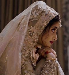 a woman in a wedding dress and veil looking off to the side with her hand on her shoulder