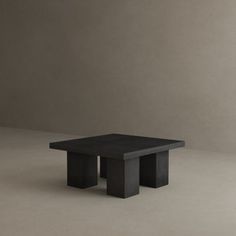 a black square table sitting on top of a white floor next to a gray wall