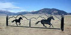 three horses running behind a fence in the desert