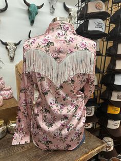 a woman's pink shirt with fringes and flowers on it in a store