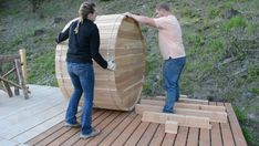 two people standing on a wooden platform with a barrel in the middle of their hands