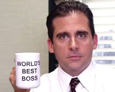 a man holding up a coffee mug with the words world's best boss on it