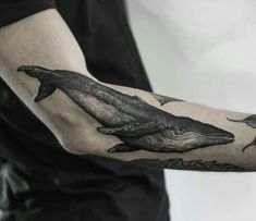 a man with a tattoo on his arm has a whale in it's hand