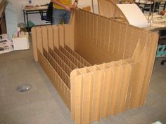 a man standing next to a cardboard box with many sections cut out and stacked on it