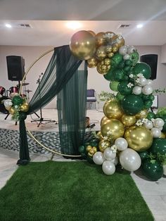 a green and gold balloon arch in the middle of a room