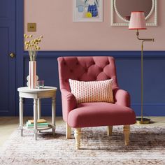 a living room with pink and blue walls, a red chair and a white table