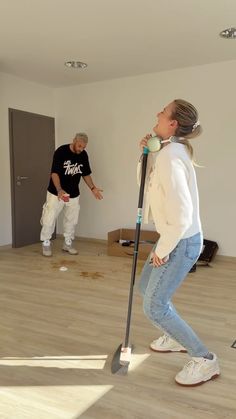 two people in an empty room with a mop