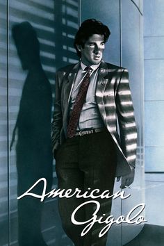 a man in a suit and tie standing next to a wall with the words american agogo written on it