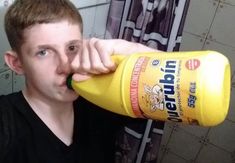 a young man drinking from a yellow bottle