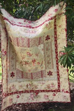 a quilt hanging from a tree in the shade