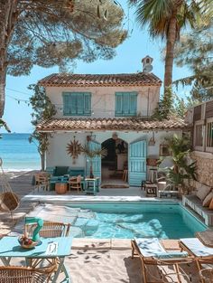 an outdoor swimming pool next to a house with blue shutters on the doors and windows