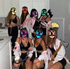 a group of women in costumes with glowing masks on their faces and holding knives, standing next to each other