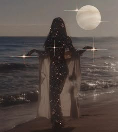 a woman standing on top of a beach next to the ocean under a full moon