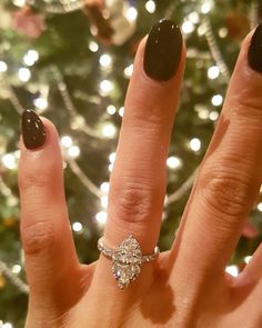 a woman's hand with a ring on it and a christmas tree in the background