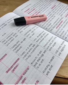 a pink pen sitting on top of an open book