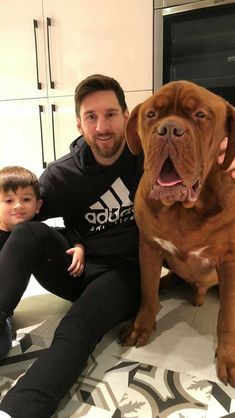 a man sitting on the floor next to a brown dog