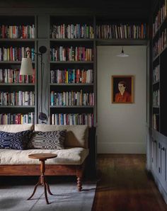 a living room with bookshelves full of books and a couch in the corner