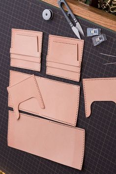 the leather pieces are being cut out and placed on top of the cutting mat with scissors