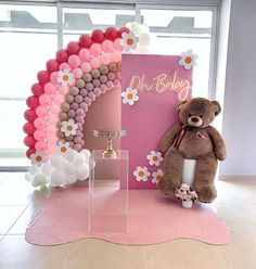 a teddy bear sitting in front of a balloon arch