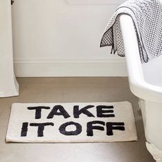 a bathroom rug that says take it off on the floor next to a bathtub