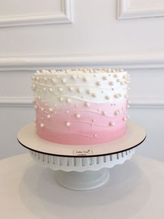 a pink and white cake with pearls on top